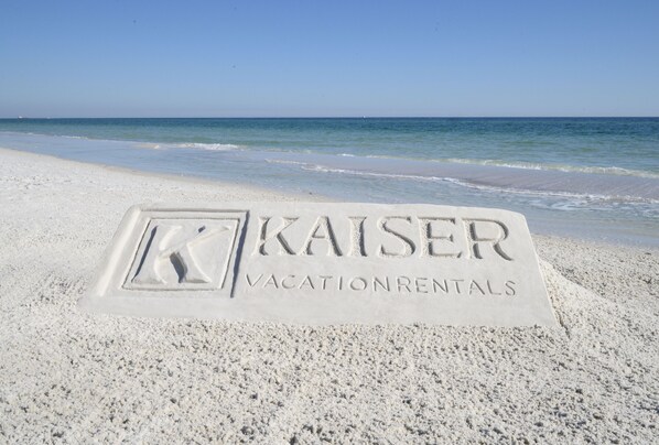A beach with a sand imprint of "Kaiser Vacation Rentals" in the sand. - Ocean Edge 9 | Beach Front, Plunge Pool, Boardwalk | Paradise Found by Kaiser (Orange Beach)