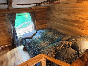 A wooden cabin bedroom with a bed, curtains, and a window. - Cozy Cabin: Peaceful Haven in the Heart of Nature (Green Mountain)