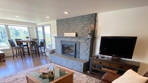 Una sala de estar con chimenea, televisor, sofá y mesa de centro.