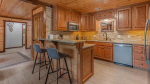 Una cocina con armarios de madera, encimera de granito, microondas, fregadero y lavavajillas.