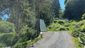 Soratie johtaa pieneen rakennukseen, jonka katto on vihreä. Rakennuksen ympärillä on tiheää kasvillisuutta ja puita.