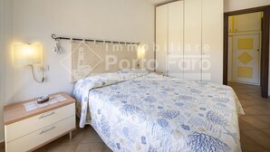 Un dormitorio con cama, mesita de noche, luces en la pared y un armario.