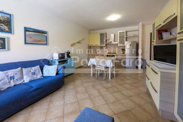 A compact living space with a sofa, a dining table, and a kitchenette.