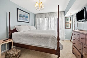 A bedroom with a four-poster bed, a chandelier, a television on a dresser, and a framed picture on the wall. - Superb oceanfront condo w/pool, sundeck, private balcony near pier for fishing, walking, crabbing (North Myrtle Beach)