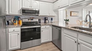 A modern kitchen with white cabinetry, stainless steel appliances, a granite countertop, and a built-in oven. - Fantastic, budget-friendly option for your next beach vacation (North Myrtle Beach)