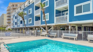 A hotel with a pool, multiple balconies, and a sign indicating shallow water and no diving. - Your Classic Oceanfront Retreat in North Myrtle Beach! (North Myrtle Beach)