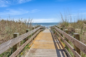 A wooden boardwalk leading to a beach with a clear view of the ocean. - Your Classic Oceanfront Retreat in North Myrtle Beach! (North Myrtle Beach)