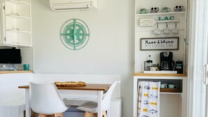 Une cuisine équipée d’une table à manger, de chaises, d’un coin café et d’un climatiseur fixé au mur.