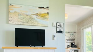 Un salon avec une cheminée, un téléviseur à écran plat et un tableau accroché au-dessus.