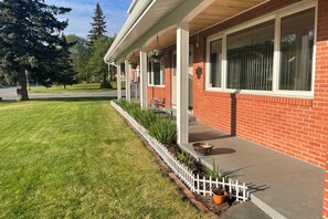 Enjoy a serene outdoor space with a covered porch, potted plants, and a bench.