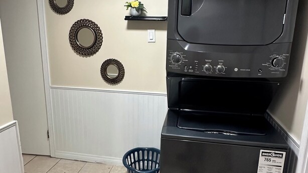 A laundry room with a front-loading washer and dryer, a blue laundry basket, and decorative wall mirrors.