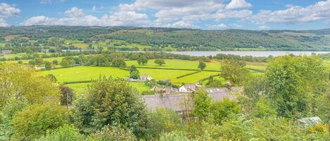 Een landelijk landschap met velden, een meer en verspreide huizen.
