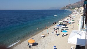 Une plage avec une eau d’un bleu limpide, des parasols et des chaises longues.