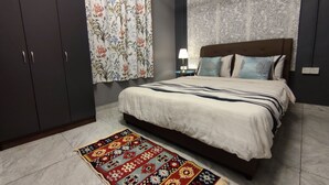 Une chambre à coucher avec un lit, une table de chevet, une lampe et un tapis à motifs.