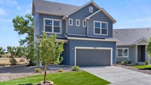 A two-story house with a garage, a well-maintained lawn, and a clear sky. - Stylish 3 Bedroom Home with Rooftop Deck (Fountain)