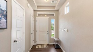 A hallway with a door, a small shelf, a vent, and a window. - Stylish 3 Bedroom Home with Rooftop Deck (Fountain)