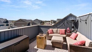 A rooftop patio with a wicker sofa set, a small wooden table, and a lantern. - Stylish 3 Bedroom Home with Rooftop Deck (Fountain)