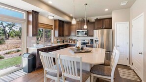 A modern kitchen with a large island, dark wood cabinets, stainless steel appliances, and a view of the outdoors. - Stylish 3 Bedroom Home with Rooftop Deck (Fountain)