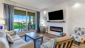 A living room with a sofa, coffee table, patterned armchair, and a fireplace.