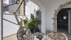 Une terrasse avec des chaises en osier, une table et des plantes en pot.
