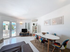 A modern living room with a dining area, a television, and a view of the outside.