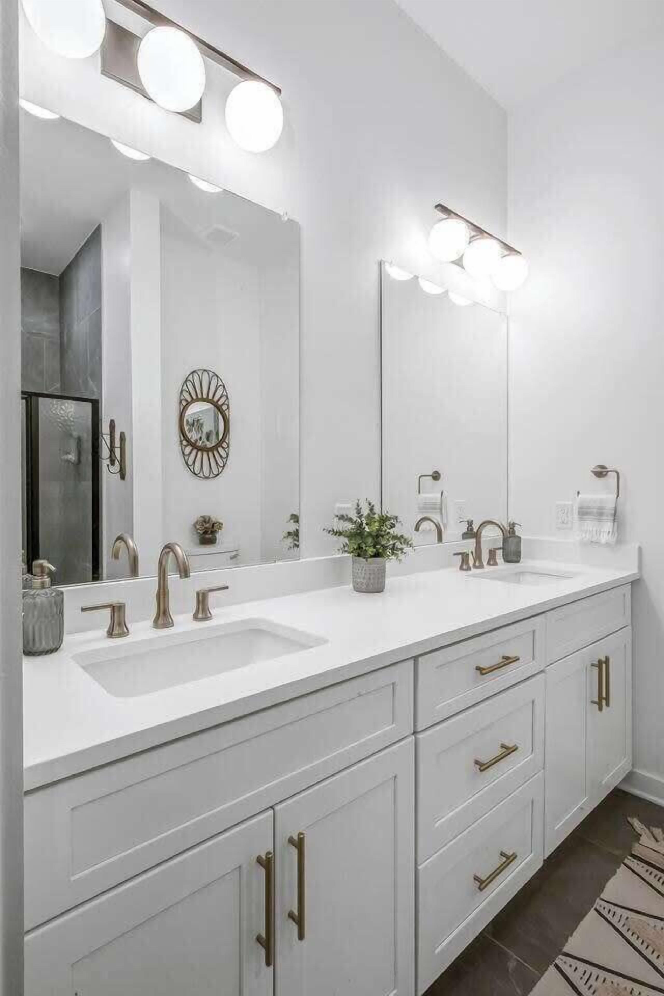 A modern bathroom with a double sink vanity, large mirror, and wall-mounted lighting.