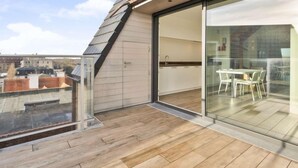 A modern apartment with a balcony, a sliding glass door leading to a dining area, and a view of the cityscape. - L'Espérance sur mer by Interhome (Bredene)