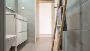 Un baño moderno con un tocador blanco, un espejo y un perchero para toallas.
