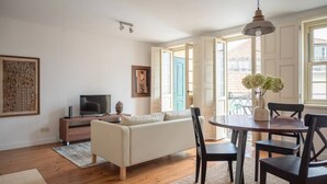 Una sala de estar con sofá, televisión y mesa de comedor con sillas.