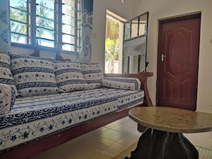 Une pièce avec un canapé, une table ronde et une porte.