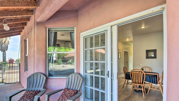 A patio area with two Adirondack chairs, a dining table with chairs, and a sliding glass door leading to an interior space. - Rejuvenating Retreat w/ Ideal Eloy Location! (Eloy)