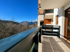 Un balcon avec vue sur les montagnes, une balustrade en bois et un sol carrelé.