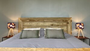 A bed with a wooden headboard, two bedside tables with lamps, and two green pillows. - Le Cosy - Towncenter (Bayeux)