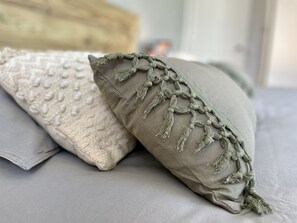 Twee kussens met een geribbelde en gevlochten rand op een bed.