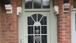 Una porta bianca con un vetro ed una decorazione a forma di cuore.