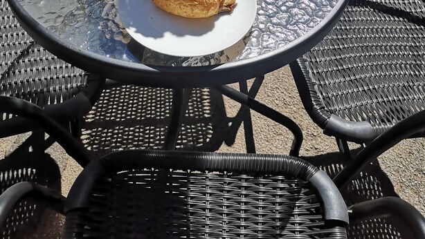 Un tavolo rotondo in vetro con prodotti per la colazione, tra cui croissant, succo d'arancia e un vaso con rose rosse.