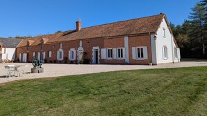 Un bâtiment de deux étages en briques, avec des éléments décoratifs blancs et un toit recouvert de tuiles.