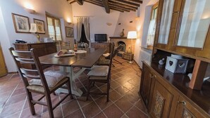 A dining area with a wooden table and chairs, a fireplace, and a television. - Typical Tuscan Cottage with swimming pool and park, five minutes from San Galgano (Monticiano)