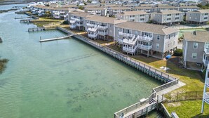 A waterfront residential area with multi-story buildings, a dock, and a clear view of the water. - Ocean Isle Beach Getaway Is A Slice Of Heaven (Ocean Isle Beach)