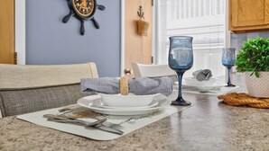 A dining area with a table set for two, featuring a white plate, a bowl, a glass, and a napkin. - Ocean Isle Beach Getaway Is A Slice Of Heaven (Ocean Isle Beach)