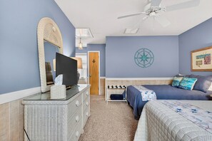 A bedroom with a television, dresser, bed, and a ceiling fan. - Ocean Isle Beach Getaway Is A Slice Of Heaven (Ocean Isle Beach)