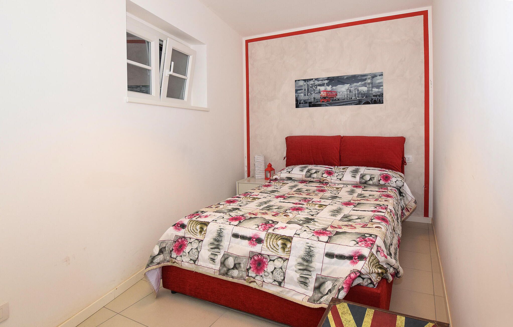 Een kleine slaapkamer met een enkel bed, een raam en een lijst met een afbeelding aan de muur.