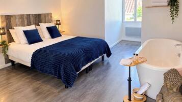 Un dormitorio moderno con una cama grande, una bañera y una estatua.