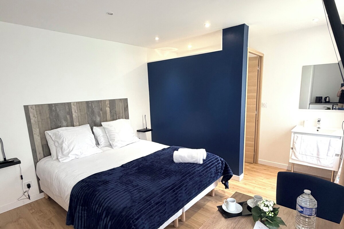 Una habitación de hotel moderna con cama, mesita de noche y un escritorio con silla.