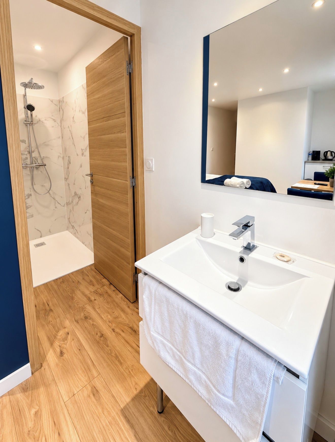 Une salle de bain moderne avec un lavabo blanc, un miroir et un espace douche.