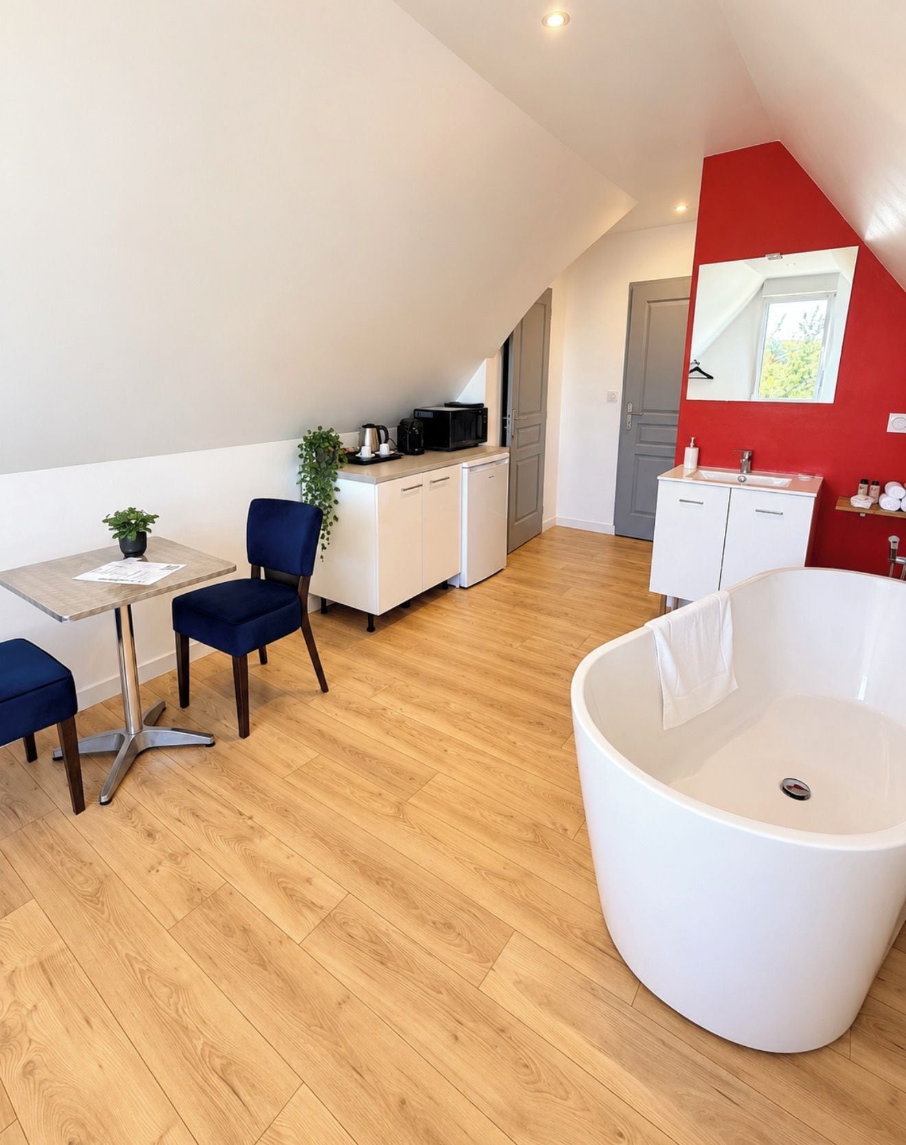 Een moderne kamer met een eethoek, kitchenette en een ruime badkuip.