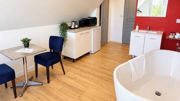 Een moderne kamer met een eethoek, kitchenette en een ruime badkuip.