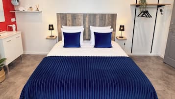 Un dormitorio con una cama grande, dos mesitas de noche, una pared de acento roja, un cabecero de madera y una planta colgante.