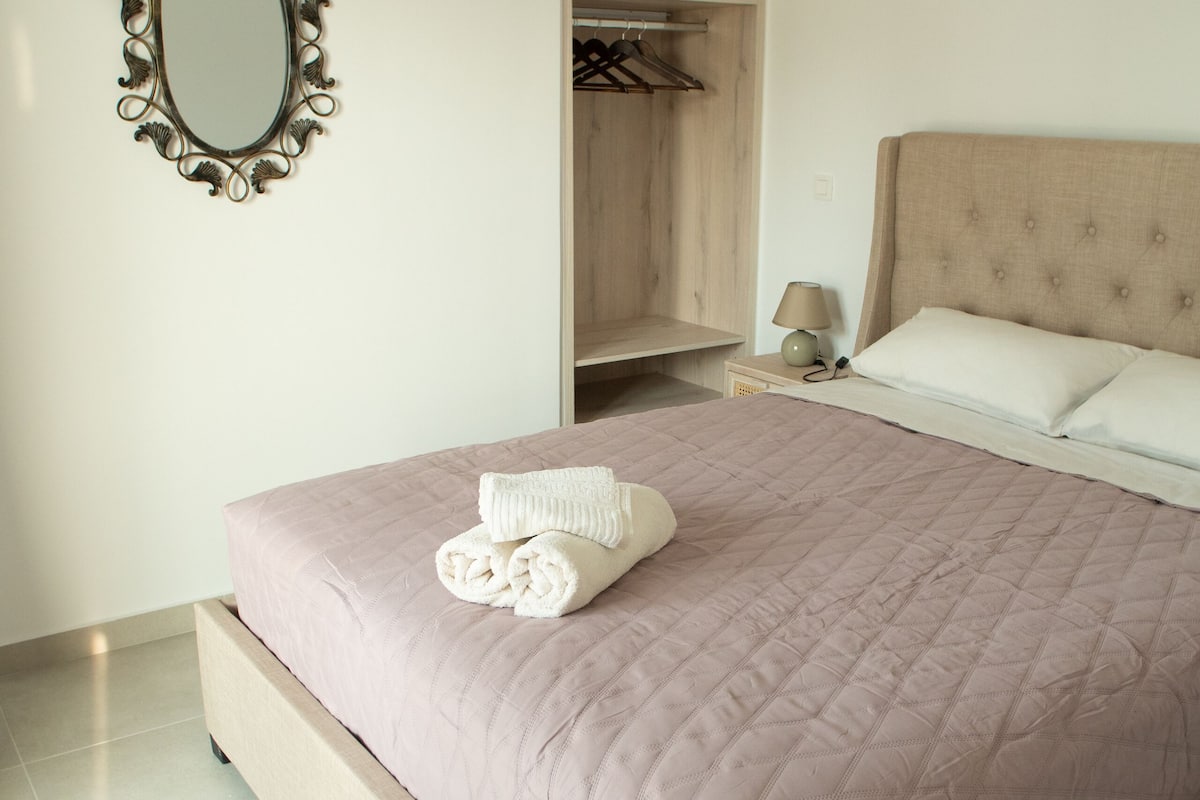 A neatly made bed with a quilted bedspread, a bedside lamp, and a wooden nightstand.