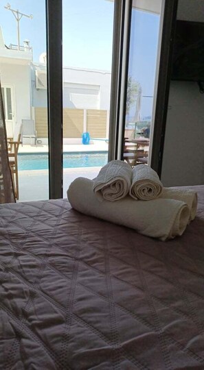 Cama com cobertura acolchoada e duas toalhas enroladas.